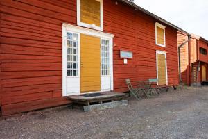 a red building with a white door and a bench at Gården in Östersolf