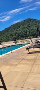 a deck with benches and a pool with a mountain at Serra & Sossego in Araras Petropolis