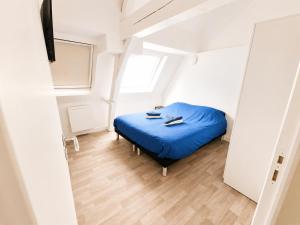 a small bedroom with a blue bed and a window at Loft lumineux & cosy sous les toits in Roubaix