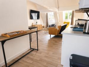 a kitchen with a counter and a living room at Loft lumineux & cosy sous les toits in Roubaix