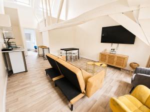 a living room with a couch and a flat screen tv at Loft lumineux & cosy sous les toits in Roubaix
