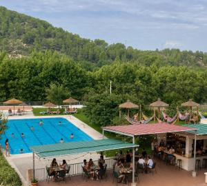 a swimming pool with people sitting at tables in front of it at Hostal Boutique Restaurante El Algars in Caseras