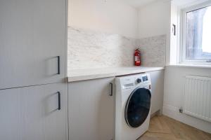 a white kitchen with a washing machine and a window at Spacious 5BR - Heart of Galashiels -Group Friendly in Galashiels
