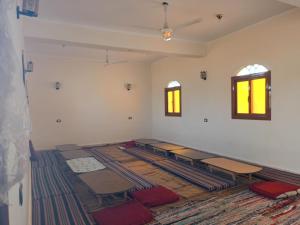 an empty room with a room with tables and windows at Manzil Al-Wahati in Bawati