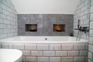 a white bath tub in a bathroom with gray tiles at Little Orchard House Self-catering Garden View apartment in Salcombe +33 photos