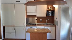 a kitchen with white cabinets and a sink at Chez Néné in Châtillon +6 photos