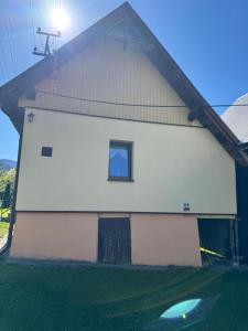 a white building with a window and a frisbee in the grass at Domek u Krzyśka in Słopnice +1 photo
