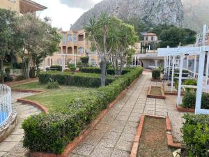 a courtyard with trees and a building and a mountain at Ashur mondello in Palermo