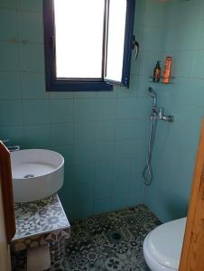 a bathroom with a sink and a toilet and a window at gialos house in Livadia