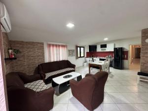a living room with a couch and chairs and a kitchen at Apartmani Natura in Sanski most