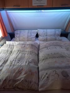 a bed with pillows on it in a room at Ferienwohnwagen Rudolf in Coswig