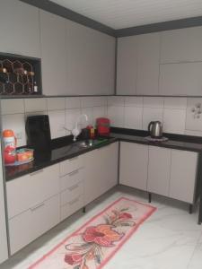 a kitchen with white cabinets and a pink rug at Casa J&G in Fazenda Rio Grande