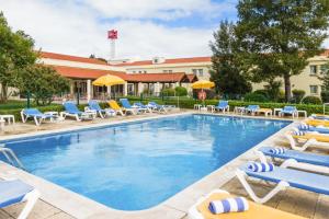 a pool with chairs and tables in it at Hotel ibis Setubal in Setúbal