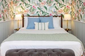 a bedroom with a bed with blue pillows and floral wallpaper at Breakwater Inn in Kennebunkport
