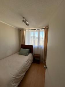 a small bedroom with a bed and a window at Departamento Centro Concepción in Concepción