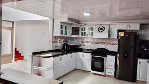 a kitchen with white cabinets and a black refrigerator at Casa cerca al Campín in Bogotá +9 photos