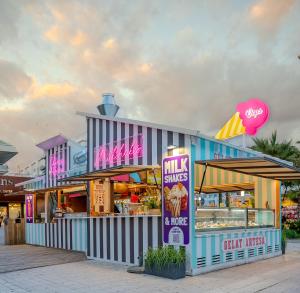 a dunkin donuts store with pink and purple signs at Aparthotel Odissea Park in Santa Susanna