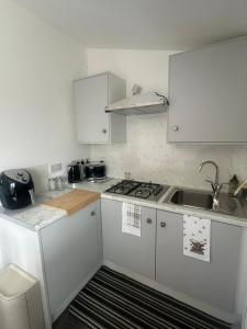 a small kitchen with white cabinets and a sink at The Old Cowhouse in Falleens