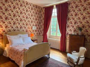 a bedroom with a bed and a chair and a window at Château de Puchesse in Sandillon