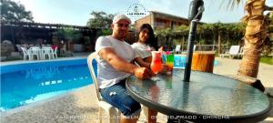 a man and woman sitting at a table near a pool at Hacienda Hotel Colpa in Chincha
