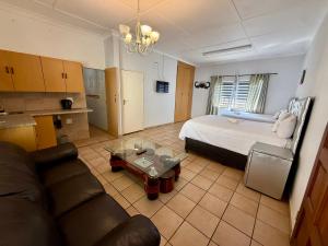 a room with a bed and a couch and a table at Blue Lantern Bed and Breakfast in Kempton Park +37 photos