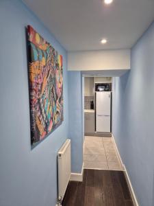 a hallway with a painting on the wall and a refrigerator at Ground floor 1 bed flat in Weymouth