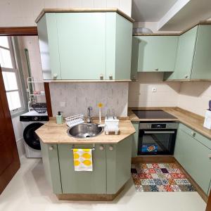 a kitchen with green cabinets and a sink at Piso en el Corazón de Ferrol in Ferrol
