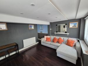 a living room with a gray couch and orange pillows at Ground floor 1 bed flat in Weymouth