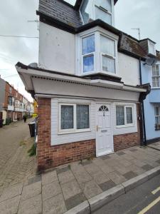 a small house with a white door on a street at Ground floor 1 bed flat in Weymouth