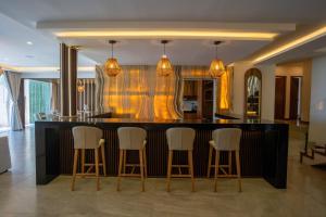 a kitchen with a bar with white bar stools at Villa Magdalena - 7BR - Oceanfront with Heated Pool in Cancún