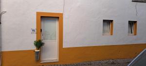 a white and orange building with a door and a potted plant at Elvasguesthouse in Elvas