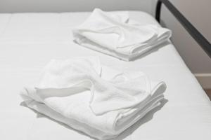 two white towels sitting on top of a bed at High-end Modern 3BR 3BA Condo Assembly Square in Somerville +19 photos