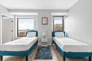 two beds in a room with two windows at High-end Modern 3BR 3BA Condo Assembly Square in Somerville