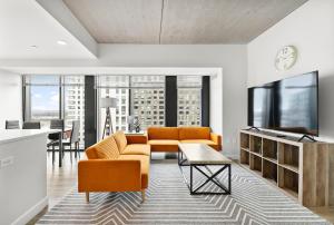 a living room with orange furniture and a flat screen tv at High-end Modern 3BR 3BA Condo Assembly Square in Somerville