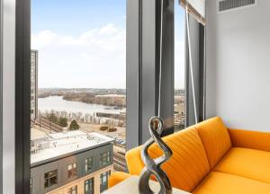 an orange couch in a room with a large window at High-end Modern 3BR 3BA Condo Assembly Square in Somerville