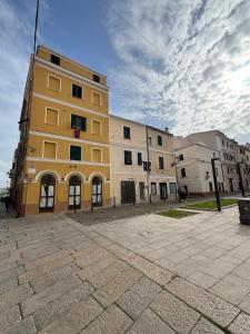 a yellow building on the side of a street at The three bell towers apartment in Alghero