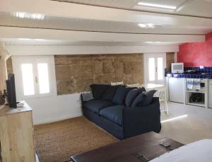 a living room with a blue couch and a kitchen at The three bell towers apartment in Alghero