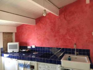 a kitchen with a red wall and a sink at The three bell towers apartment in Alghero +31 photos