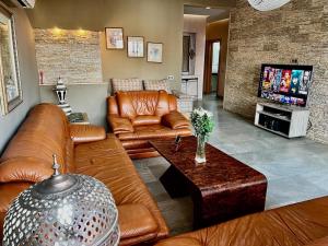 a living room with leather furniture and a flat screen tv at Sudresidence in Agadir