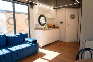a living room with a blue couch and a kitchen at Selene Houseboat Polańczyk in Polańczyk