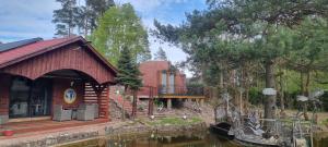 a log cabin with a deck next to a body of water at Nestor Baron in Borkowo