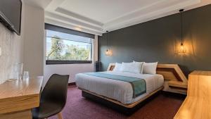 a hotel room with a bed and a desk and a window at Uniko Living Roma in Mexico City