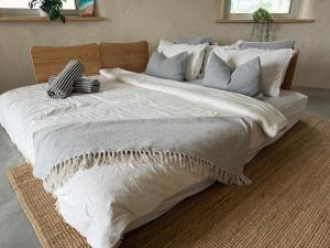 a large bed with white sheets and pillows on it at Whales and Bales in Bremer Bay