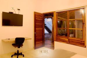 a room with a desk and a chair and a television at Hotel Madera y Tierra in Tame