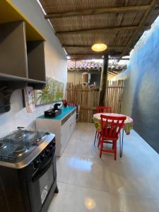 a kitchen with a stove and a table with a chair at Chalé Rosa in Trancoso