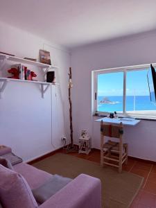 a living room with a couch and a desk and a window at Zambujeira Lounge in Zambujeira do Mar