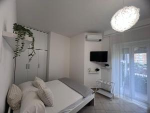 a white bedroom with a bed and a tv at TERRACINA Central Rooms in Terracina