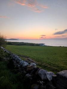 a sunset over a field with a stone wall at Seabreeze Apartment in Westport +8 photos