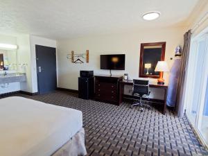 a hotel room with a bed and a desk and a television at SilverStone Inn North Spokane in Spokane