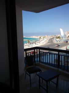 a balcony with a chair and a view of the beach at Royal Crown Hotel Marsa Matruh in Marsa Matruh